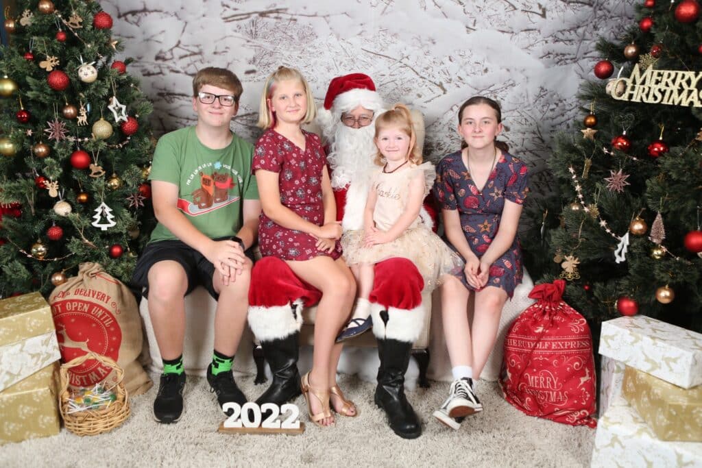A boy and thgree little girls posing for a photo with santa claus